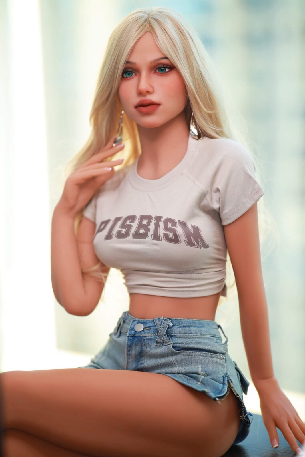 DutchDoll Lilly 158 cm Sexpuppe sitzend in weißem Crop Top mit Schriftzug und Jeansshorts, blonde Haare