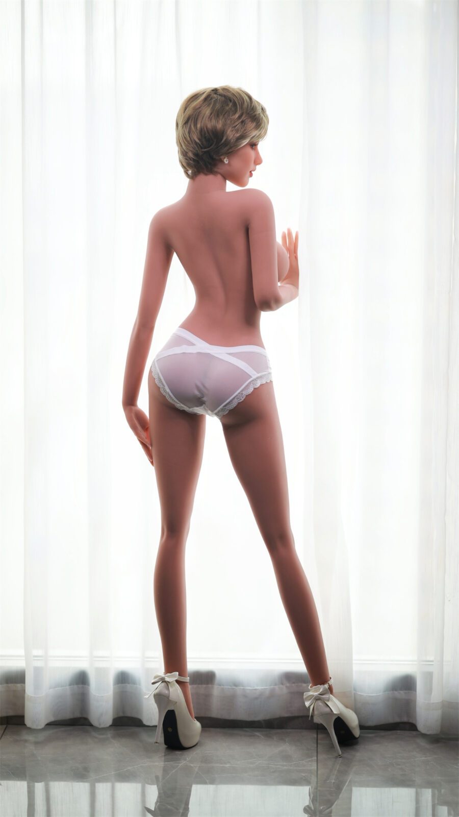 DutchDoll Kate 159 cm секс кукла изглед отзад, бели бикини и токчета, стояща до прозорец