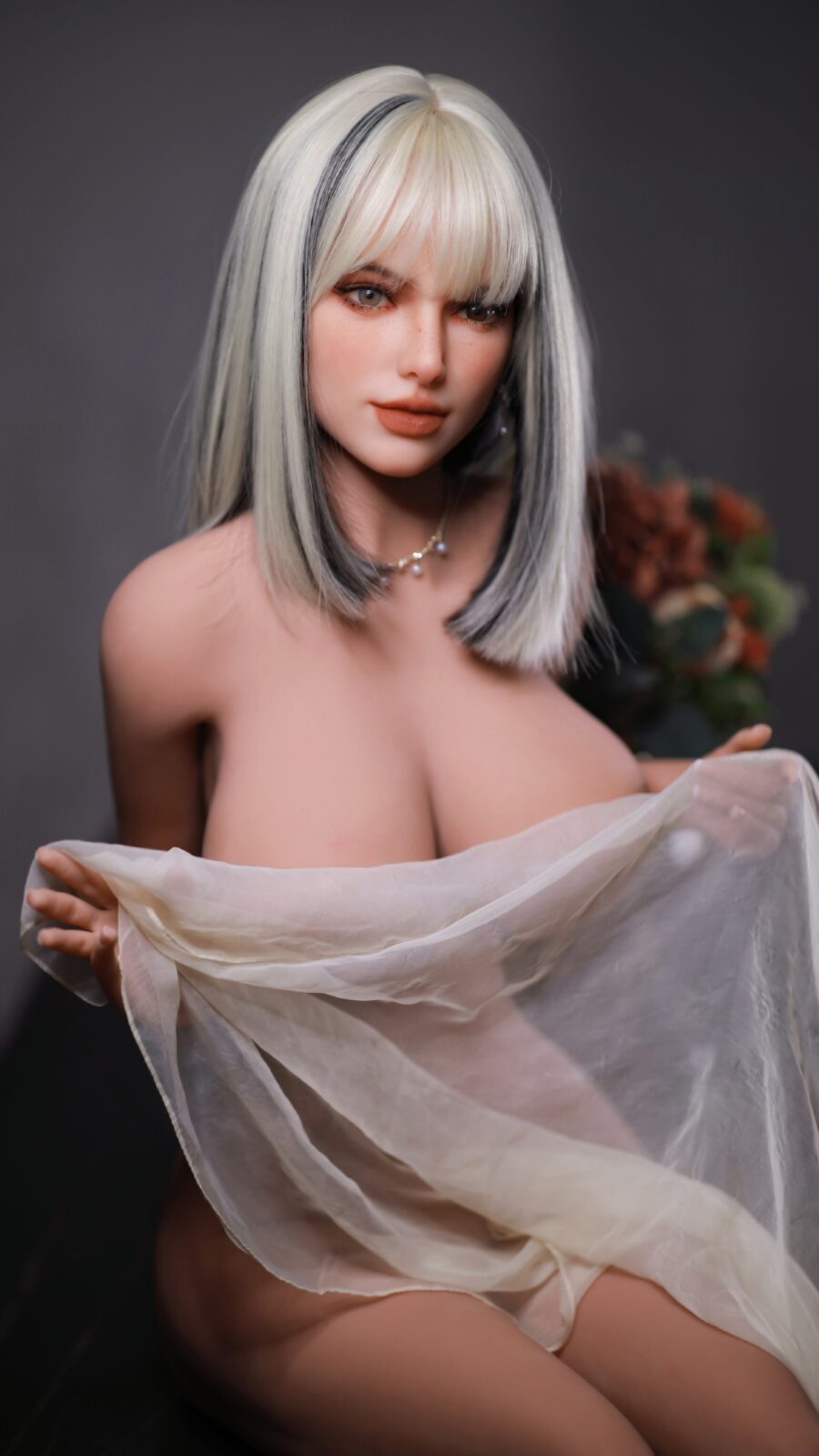 DutchDoll Tiana 159 cm lalka erotyczna z blond peruką i szarymi pasmami, trzyma przezroczystą woalkę przed ciałem